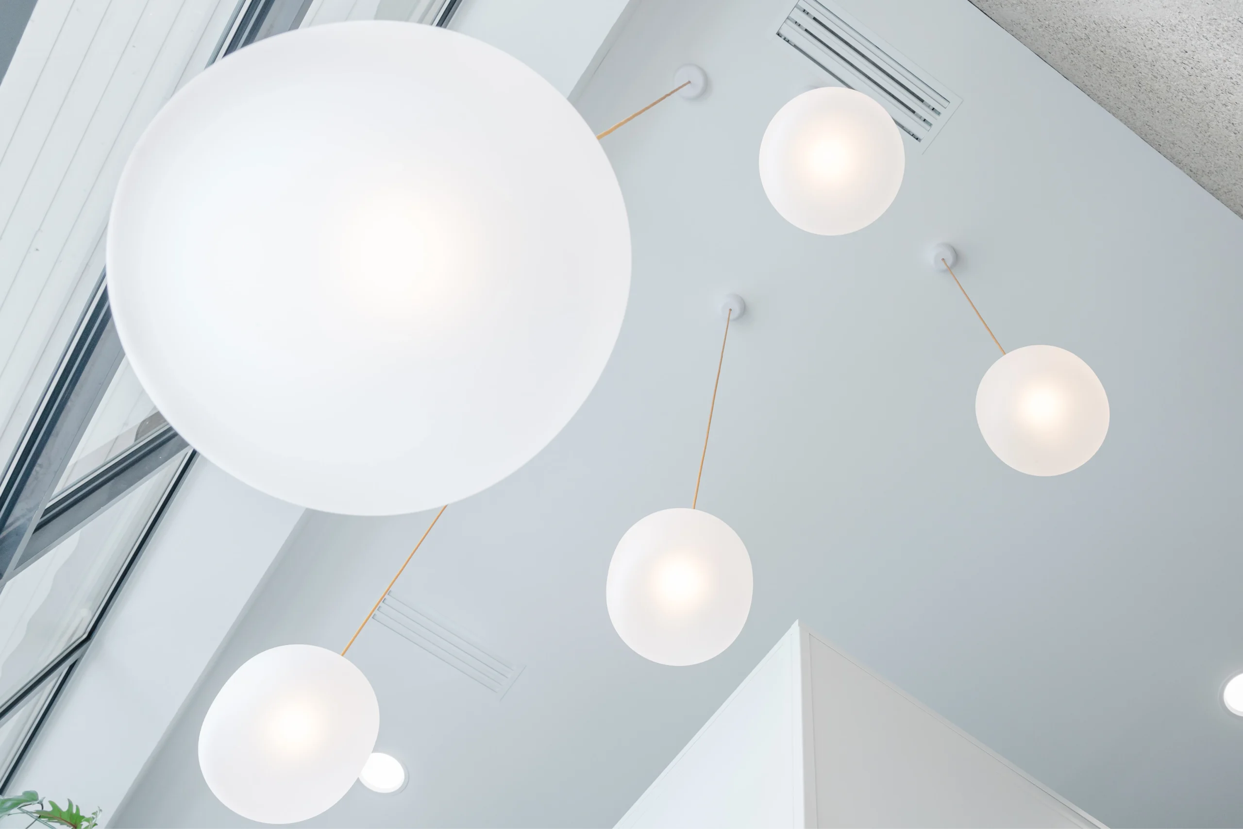 Luminaires en globes blancs suspendus sous un puits de lumière du cabinet